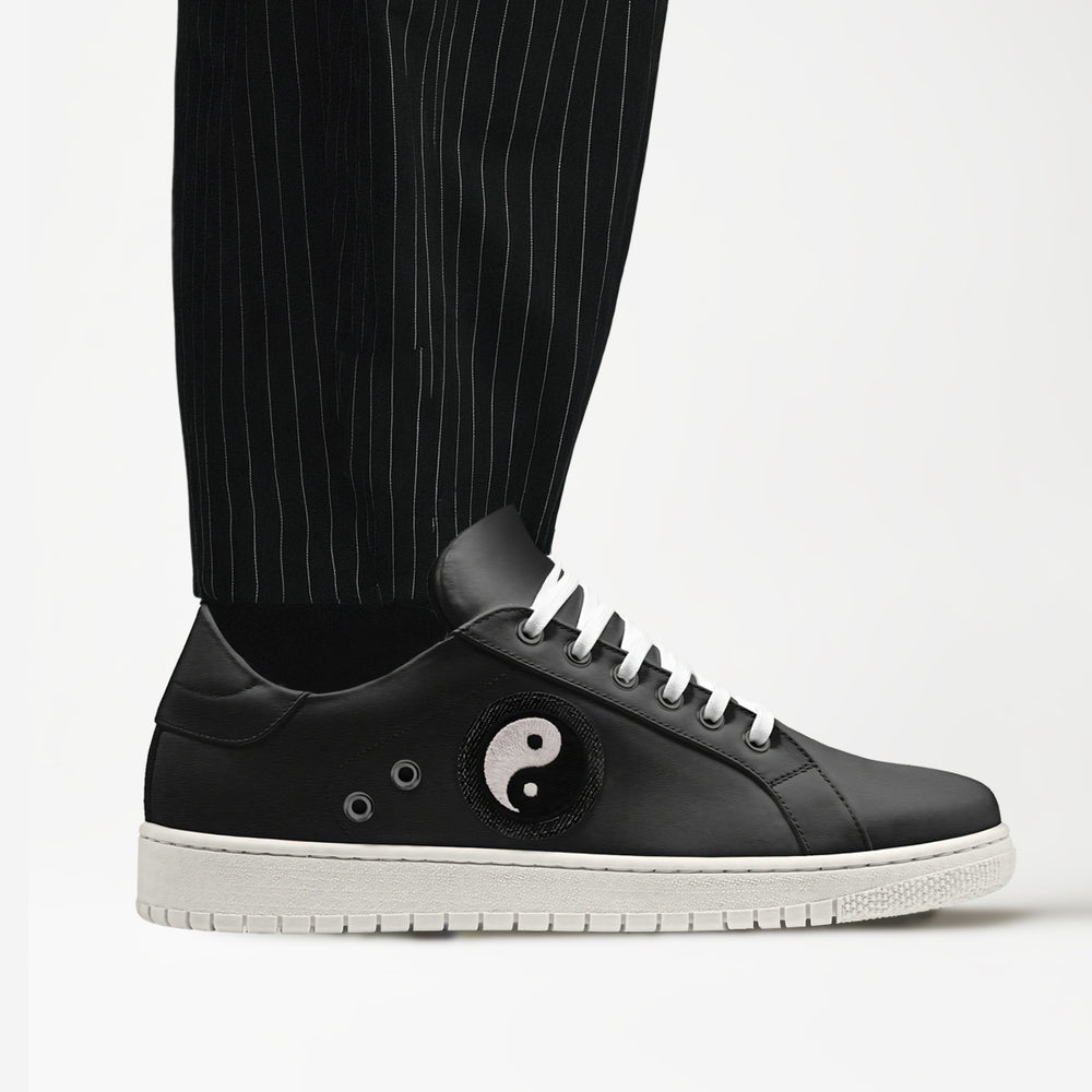 Vegan 'Gravity' sneakers in sleek low-top black, featuring a Yin-Yang patch on the side, blending eco-conscious materials with symbolic design.
