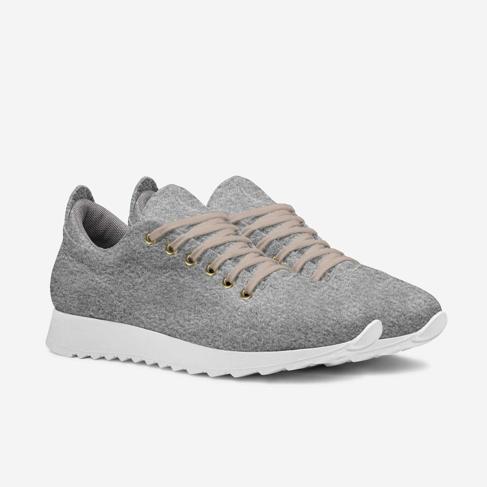 Soft grey wool low-top sneakers with white soles and comfortable texture, matched with rolled-up brown trousers.