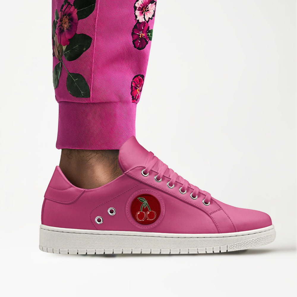 Vibrant pink sneakers with embroidered cherries emblem, paired with floral trousers for a bold, sustainable look.